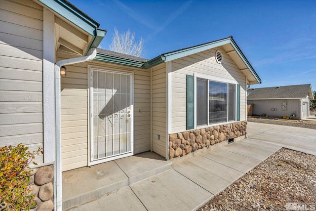 property entrance with a patio area and stone siding