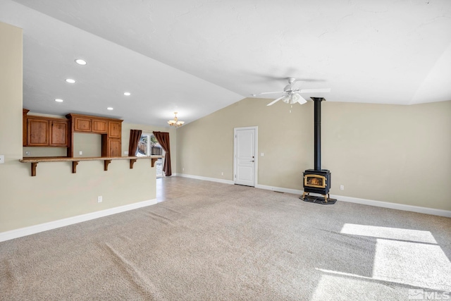 unfurnished living room featuring baseboards, light colored carpet, lofted ceiling, recessed lighting, and a wood stove