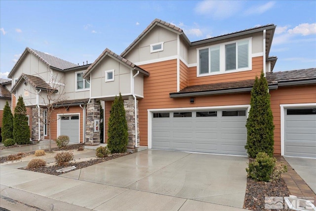 view of front of house featuring a garage, stone siding, driveway, and a tile roof