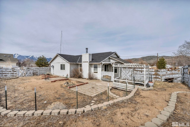 back of property featuring a patio area, a mountain view, a chimney, and a fenced backyard