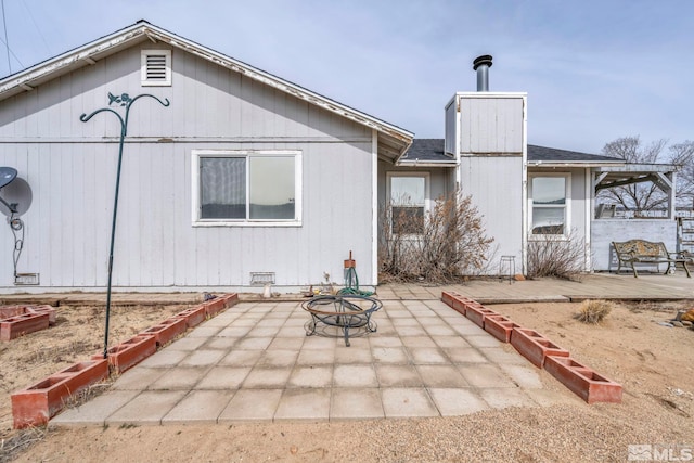 back of house with a patio area, roof with shingles, and crawl space