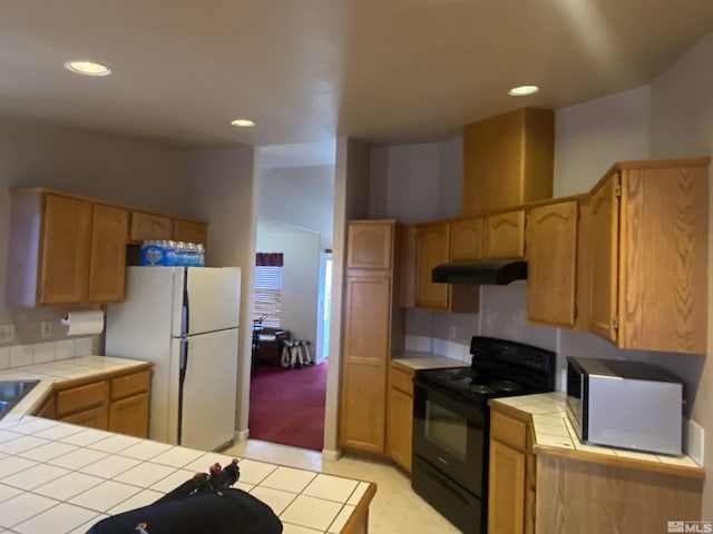 kitchen with recessed lighting, freestanding refrigerator, tile counters, black range with electric cooktop, and under cabinet range hood