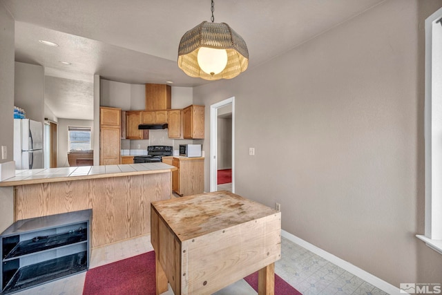 kitchen featuring black / electric stove, freestanding refrigerator, tile counters, tile patterned floors, and stainless steel microwave