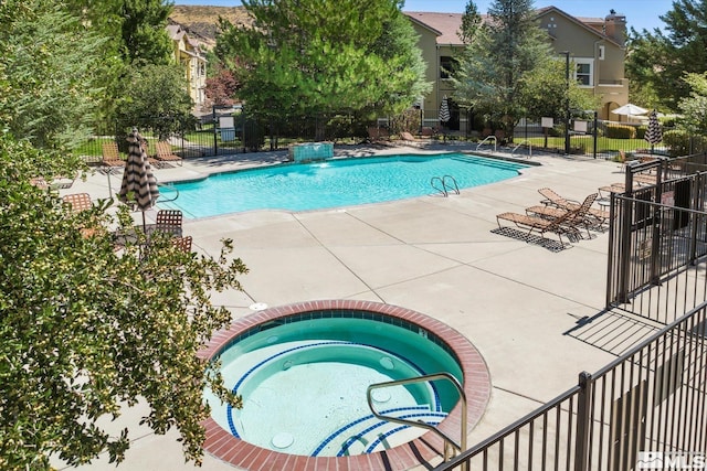 pool with a hot tub, a patio, and fence