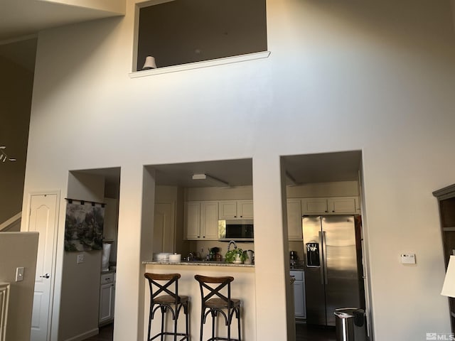 kitchen featuring a kitchen breakfast bar, stainless steel appliances, and a towering ceiling