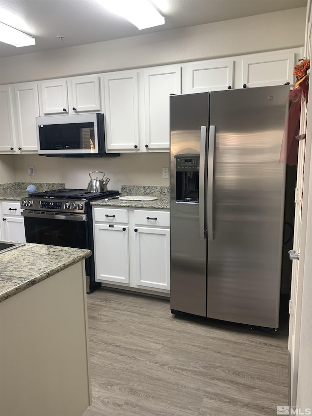 kitchen featuring white cabinets, stainless steel appliances, and light wood-style floors