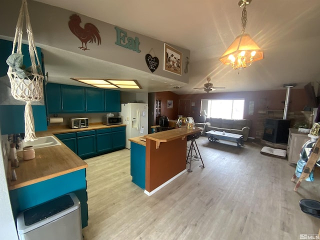 kitchen featuring stainless steel microwave, light wood-style floors, white fridge with ice dispenser, and wooden counters