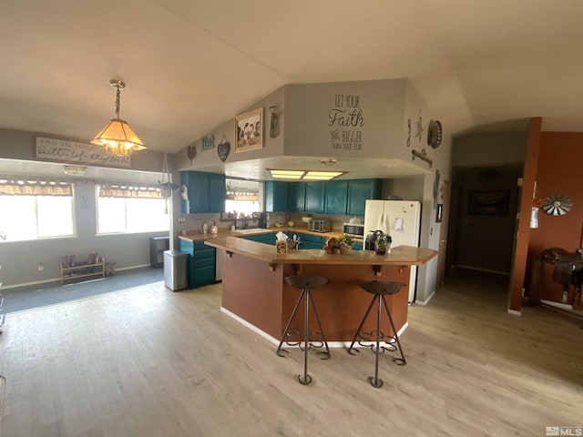 kitchen with blue cabinetry, lofted ceiling, light wood-style flooring, a kitchen breakfast bar, and freestanding refrigerator