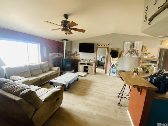 living area featuring ceiling fan, a wood stove, lofted ceiling, and wood finished floors