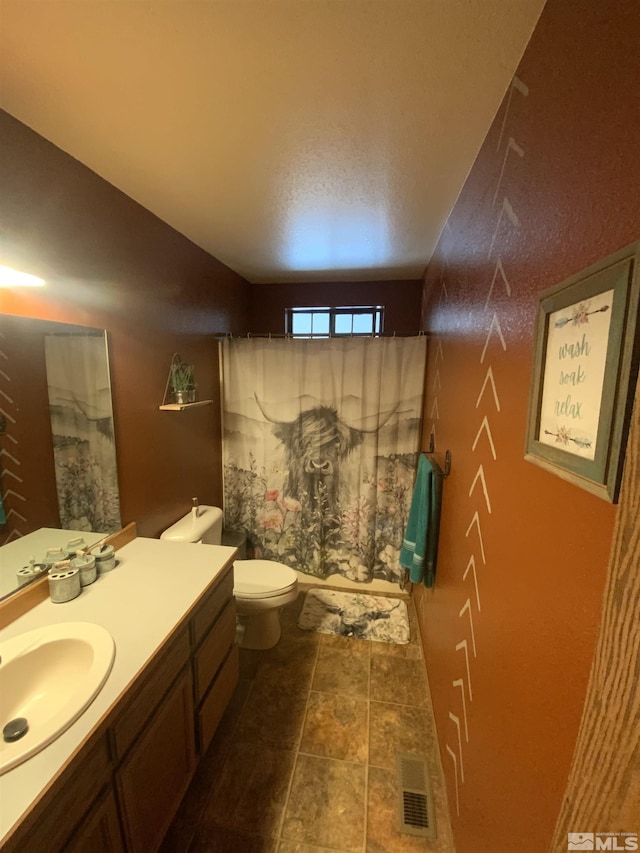 bathroom featuring vanity, toilet, and visible vents