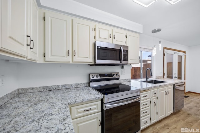 kitchen featuring a sink, light wood finished floors, white cabinetry, and stainless steel appliances