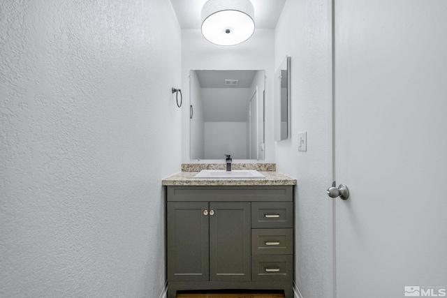 bathroom featuring vanity and a textured wall