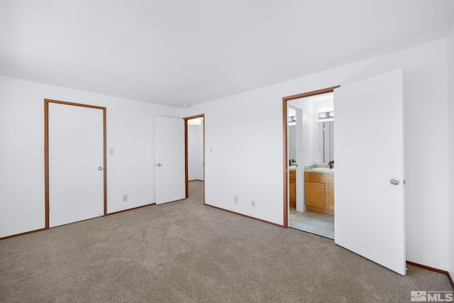 unfurnished bedroom featuring light carpet, connected bathroom, and baseboards