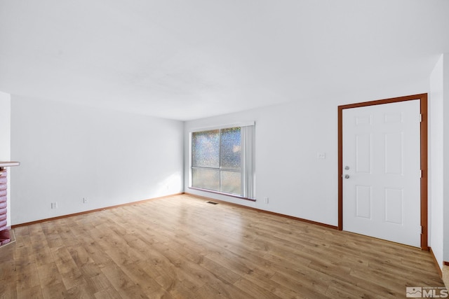 unfurnished living room featuring visible vents, baseboards, and wood finished floors