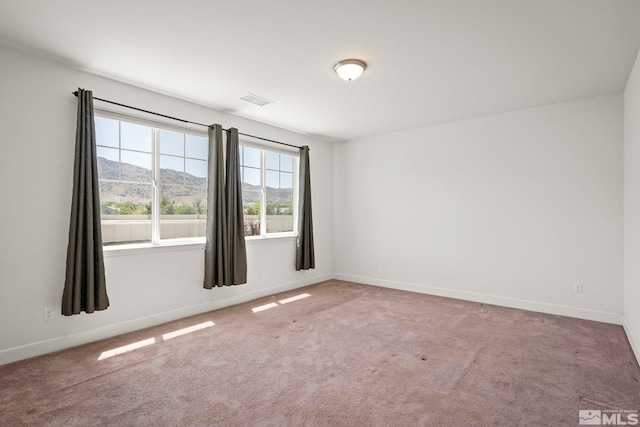 unfurnished room with visible vents, baseboards, carpet, and a mountain view