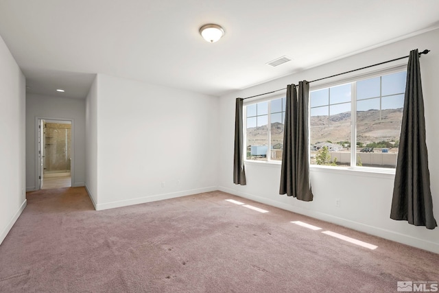 spare room with visible vents, light colored carpet, a mountain view, and baseboards