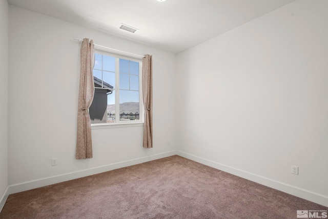 carpeted spare room with visible vents and baseboards