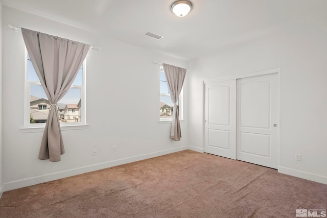 unfurnished bedroom with carpet flooring, baseboards, visible vents, and a closet