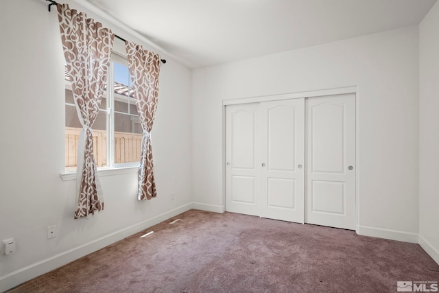 unfurnished bedroom with baseboards, carpet floors, and a closet