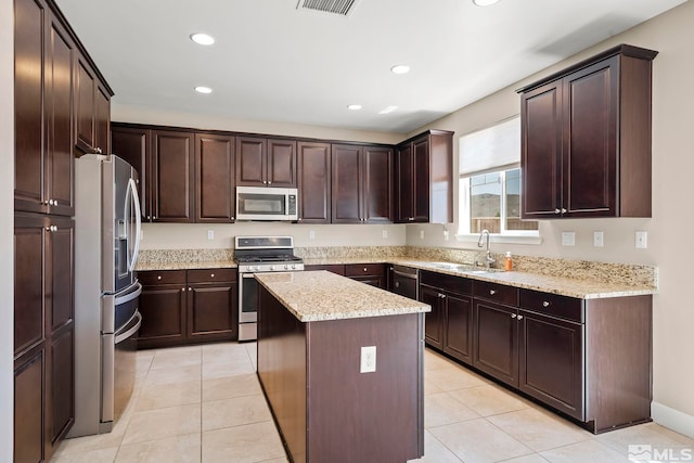 kitchen featuring a sink, a kitchen island, stainless steel appliances, light tile patterned flooring, and dark brown cabinets