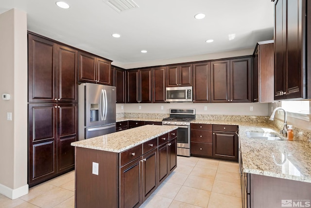 kitchen featuring light tile patterned floors, visible vents, a kitchen island, a sink, and stainless steel appliances