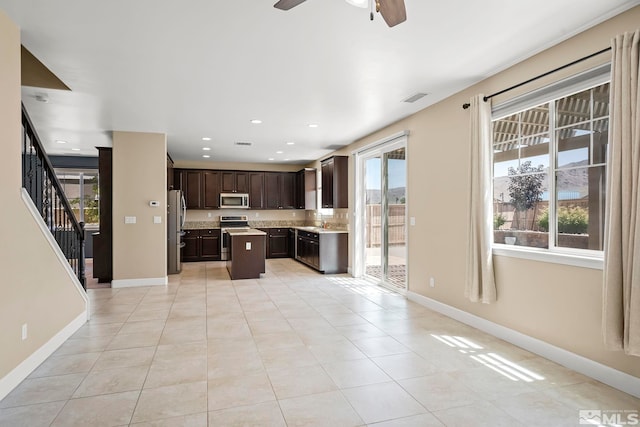 kitchen with visible vents, a kitchen island, dark brown cabinetry, light countertops, and appliances with stainless steel finishes