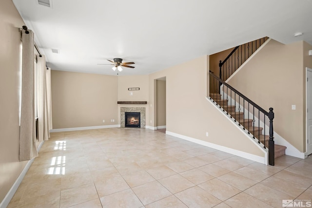 unfurnished living room with light tile patterned floors, baseboards, ceiling fan, and stairs