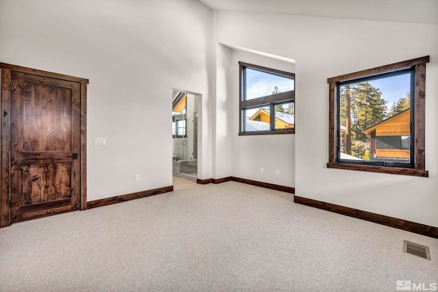 unfurnished room with visible vents, light carpet, and baseboards