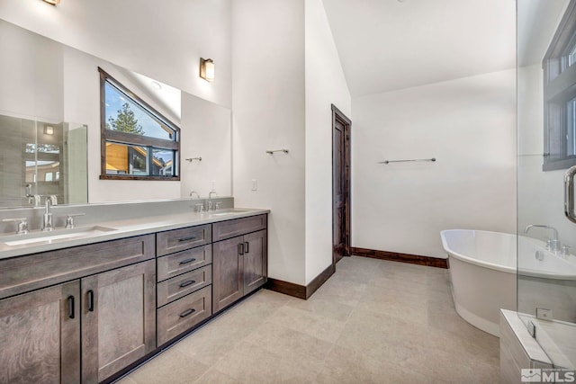 full bathroom featuring double vanity, a freestanding tub, baseboards, and a sink