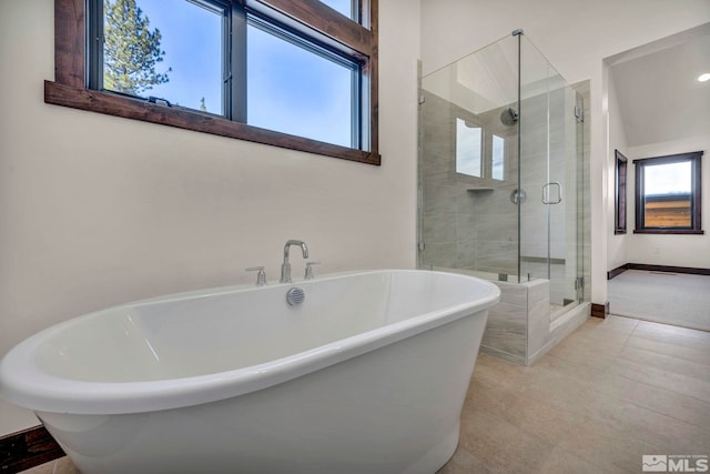 full bathroom featuring tile patterned floors, a shower stall, a freestanding bath, and baseboards