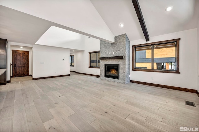 unfurnished living room with baseboards, visible vents, high vaulted ceiling, light wood-style flooring, and a fireplace