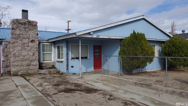 view of front of home featuring metal roof and fence