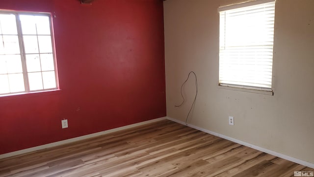 empty room with light wood-style floors, baseboards, and a wealth of natural light