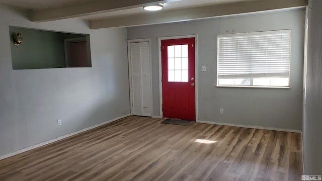 entryway with beam ceiling, wood finished floors, and baseboards