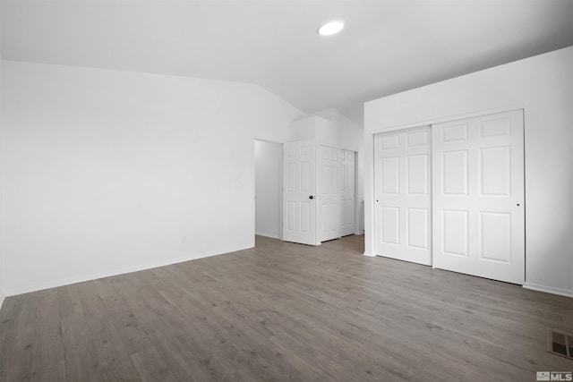 unfurnished bedroom featuring visible vents, wood finished floors, recessed lighting, baseboards, and lofted ceiling