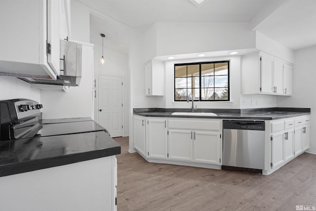 kitchen featuring dark countertops, white cabinets, stainless steel appliances, and a sink