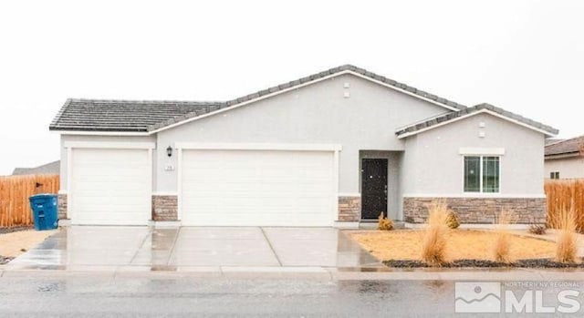 view of front of property with a garage, stone siding, driveway, and fence