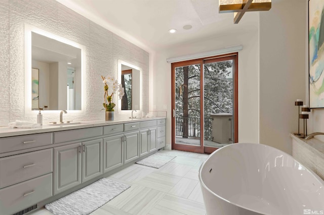 bathroom featuring a sink, visible vents, a freestanding bath, and double vanity