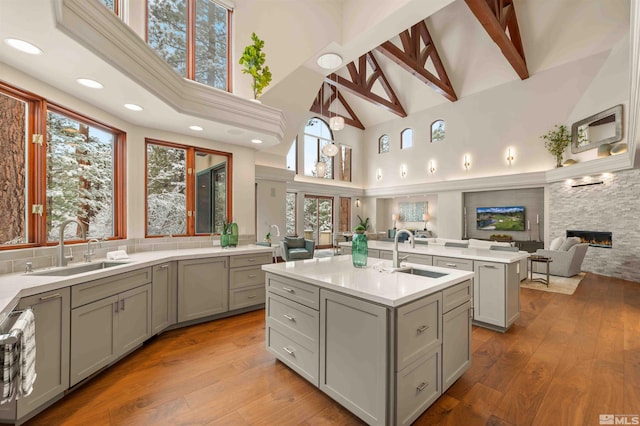 kitchen with a sink, gray cabinetry, open floor plan, and an island with sink