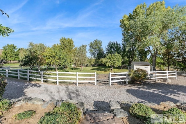 exterior space with an outbuilding, a rural view, a storage shed, and fence