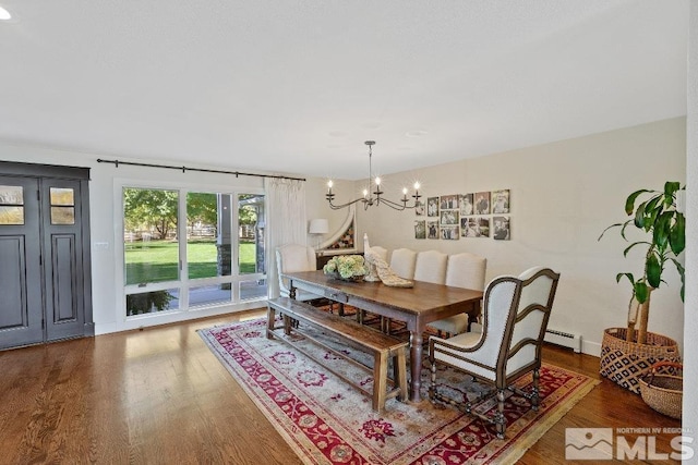 dining area featuring baseboards, baseboard heating, an inviting chandelier, and wood finished floors