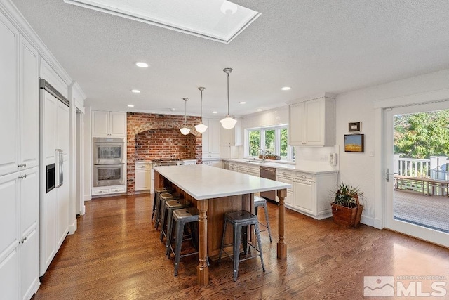 kitchen featuring a breakfast bar area, dark wood-style floors, appliances with stainless steel finishes, and a kitchen island