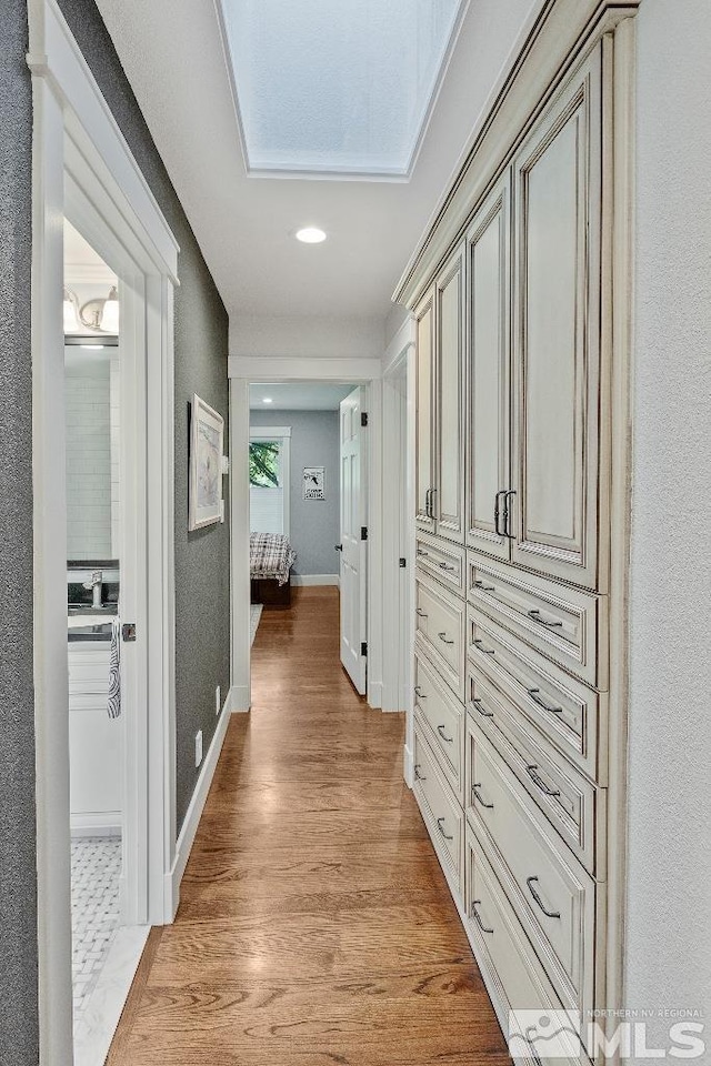 corridor featuring baseboards and light wood finished floors