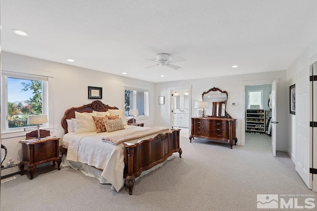 bedroom featuring recessed lighting, ceiling fan, ensuite bathroom, light carpet, and baseboard heating