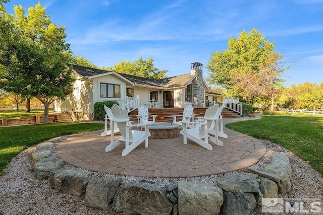 rear view of house with a yard, a patio, a fire pit, and a chimney