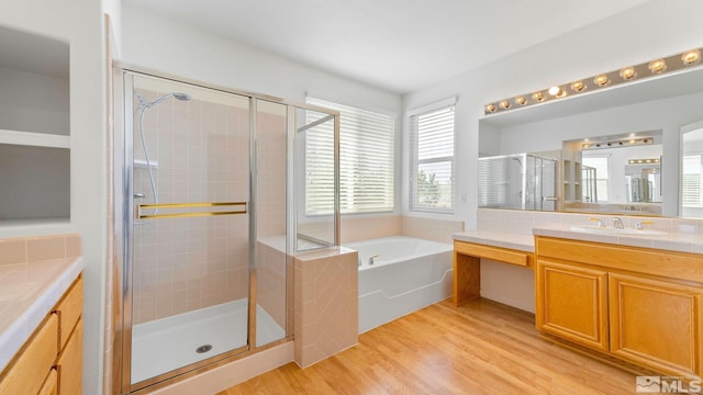 bathroom featuring a garden tub, vanity, wood finished floors, and a shower stall