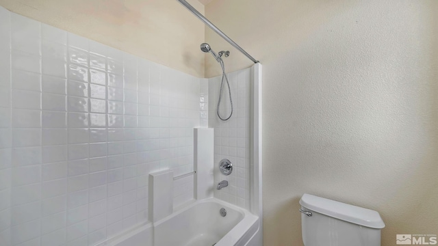 bathroom with shower / bath combination, toilet, and a textured wall