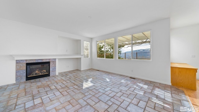 unfurnished living room with visible vents, baseboards, and a tile fireplace