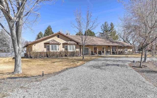 ranch-style home with stucco siding, a front lawn, and driveway