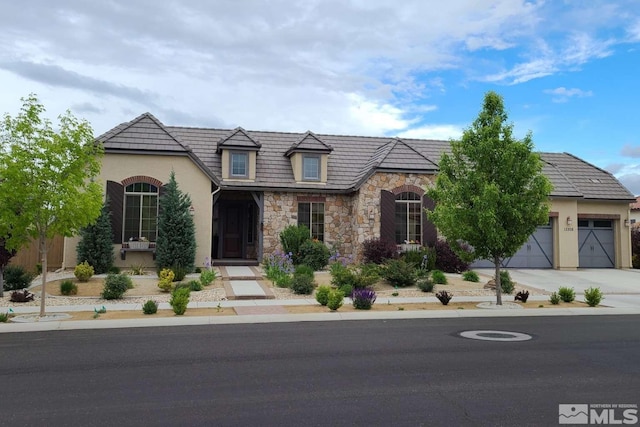 view of front of house with an attached garage, stone siding, driveway, and stucco siding